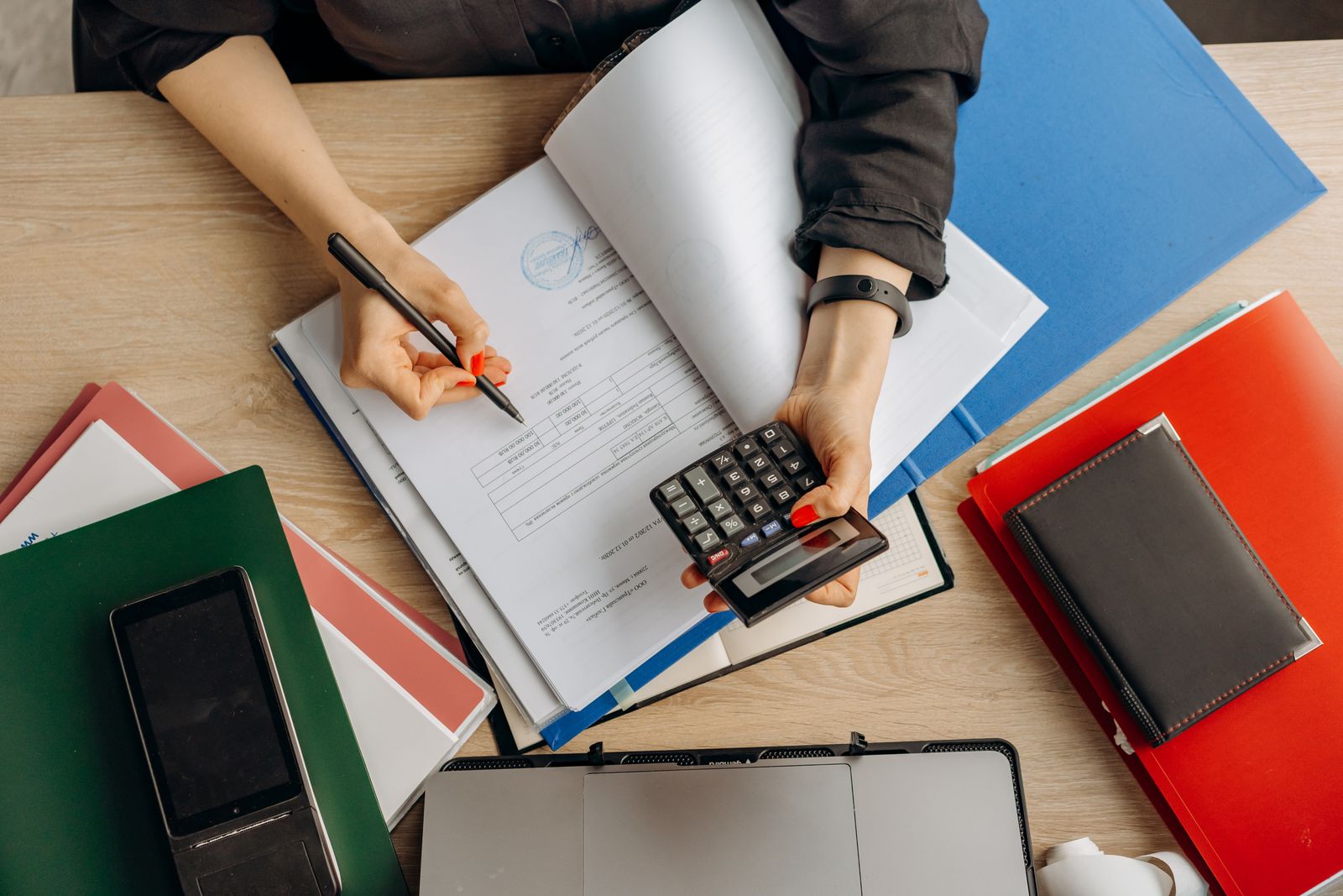 Company director working through financial paperwork with a calculator, planning salary and dividend payments
