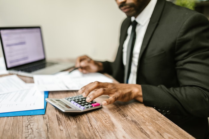 Company director reviewing company accounts paperwork with a calculator and laptop
